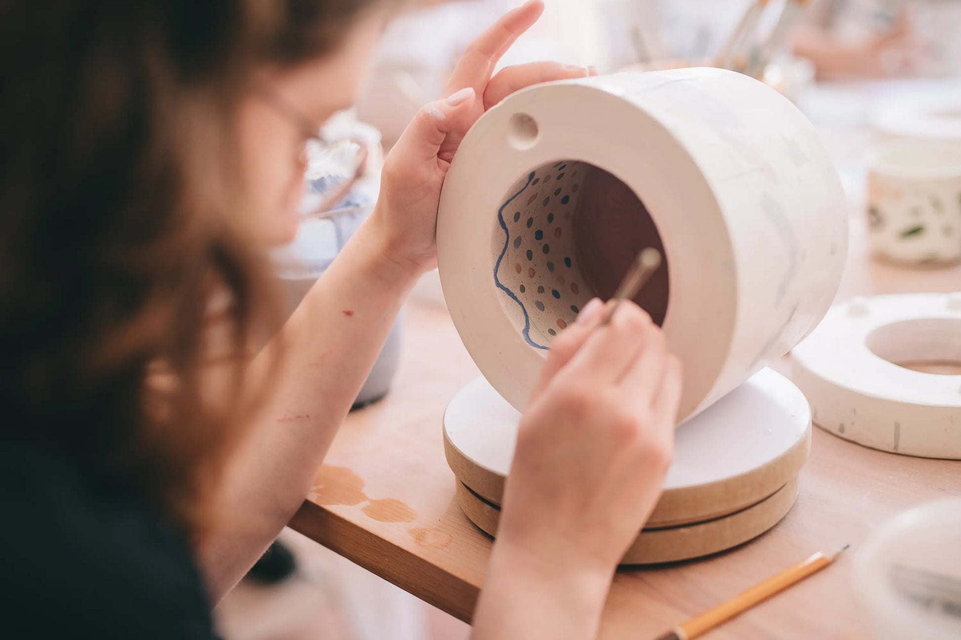 Uczestniczka warsztatu ozdabiająca formę do porcelany przy stole z narzędziami i formami - warsztat odlewania porcelany
